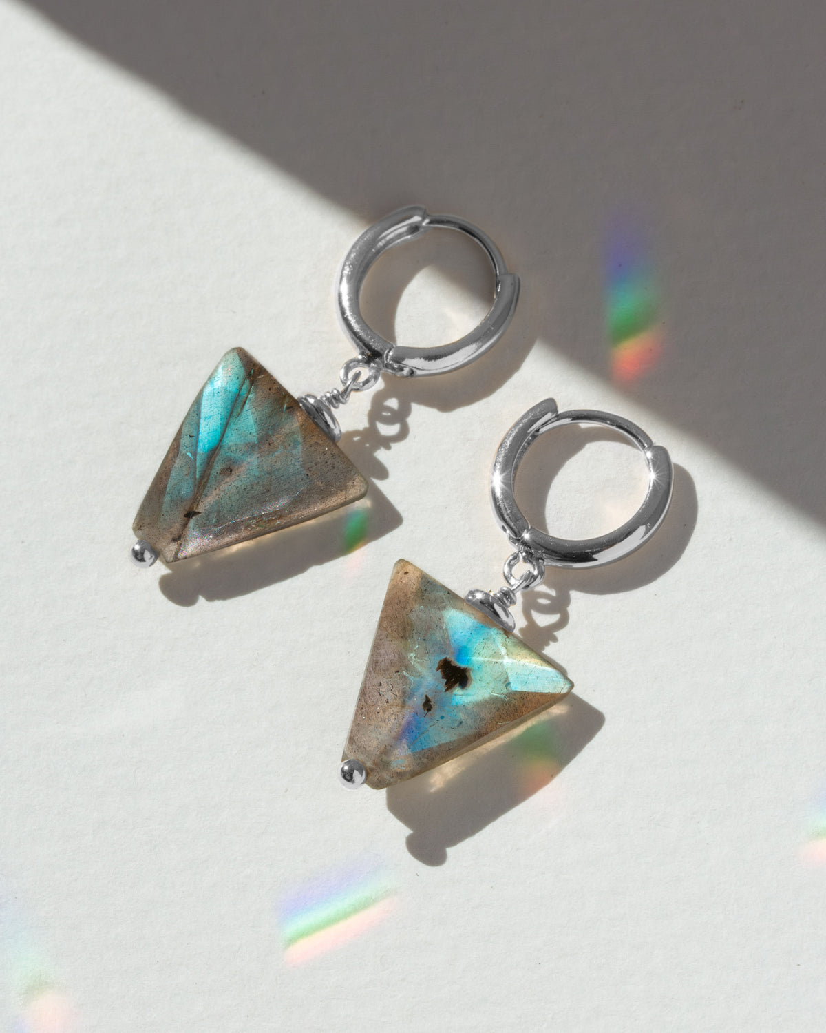 Triangular gemstone earrings on a light background