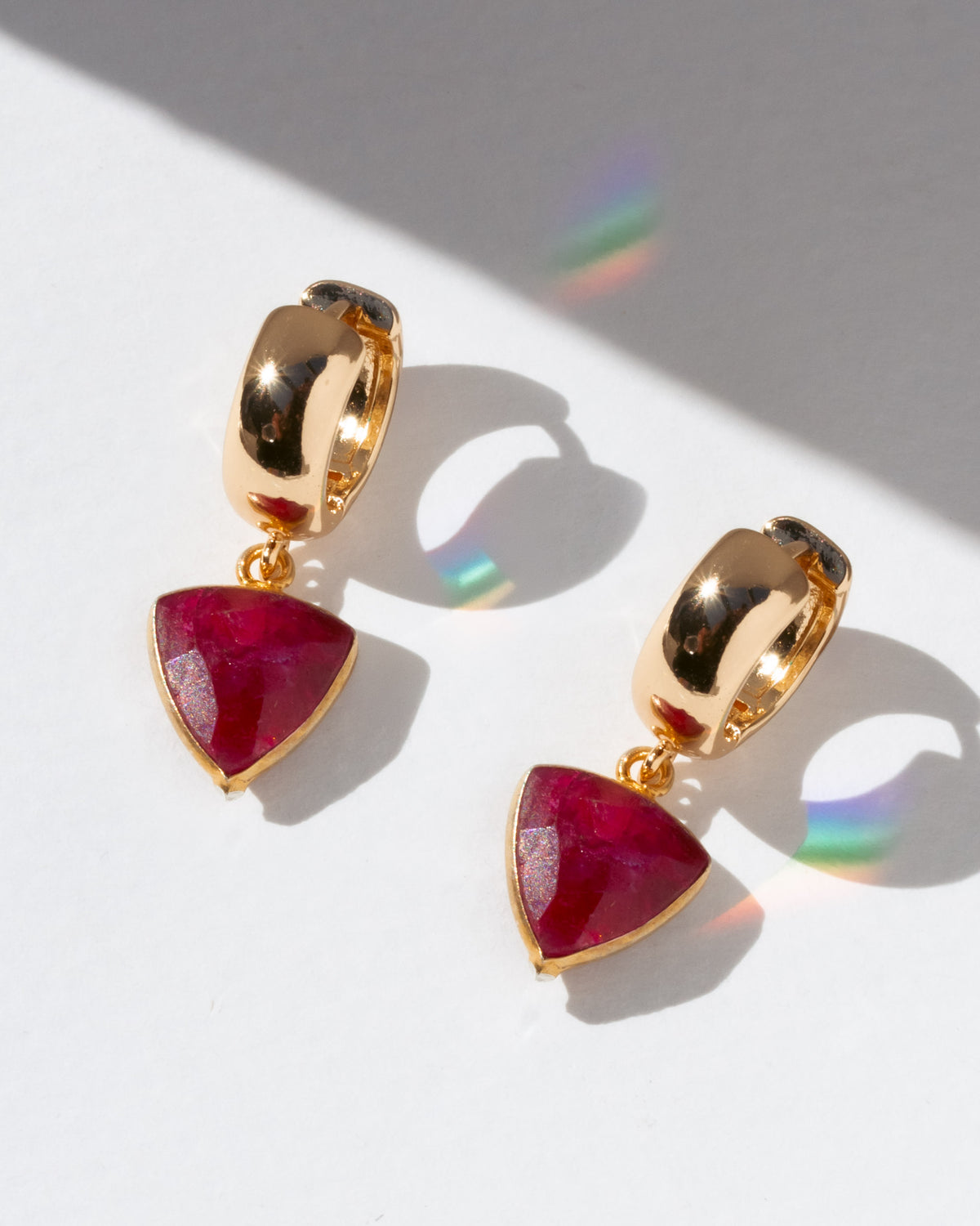 Gold earrings with red gemstones on a white background