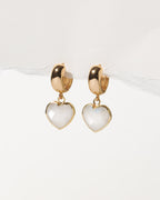Heart-shaped earrings with gold wide huggie hoops on a white background