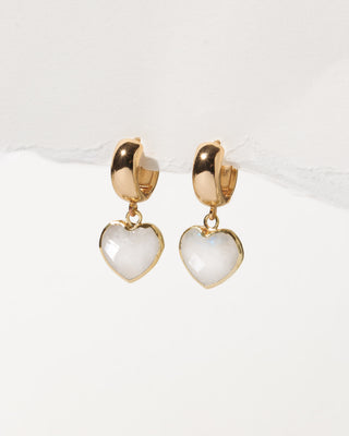 Heart-shaped earrings with gold wide huggie hoops on a white background