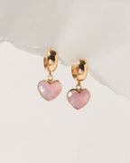 Heart-shaped earrings with pink stones and gold accents on a light background