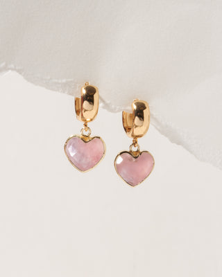 Heart-shaped earrings with pink stones and gold accents on a light background