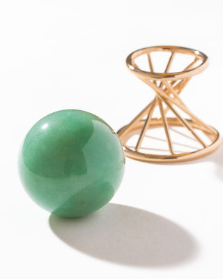 Green Aventurine sphere curio next to a gold color stand on a white surface.