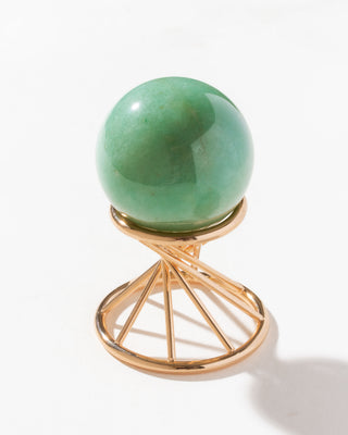 Green aventurine sphere curio sitting on a gold colored stand on a white surface.