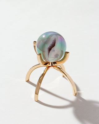 Eye Of The Beholder druzy gemstone sphere with a rainbow effect, displayed on a gold stand.