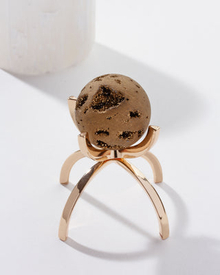 Gold colored druzy quartz sphere on a gold colored, stand against a white background