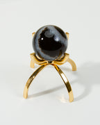 A sardonyx gemstone sphere on a gold-colored stand.