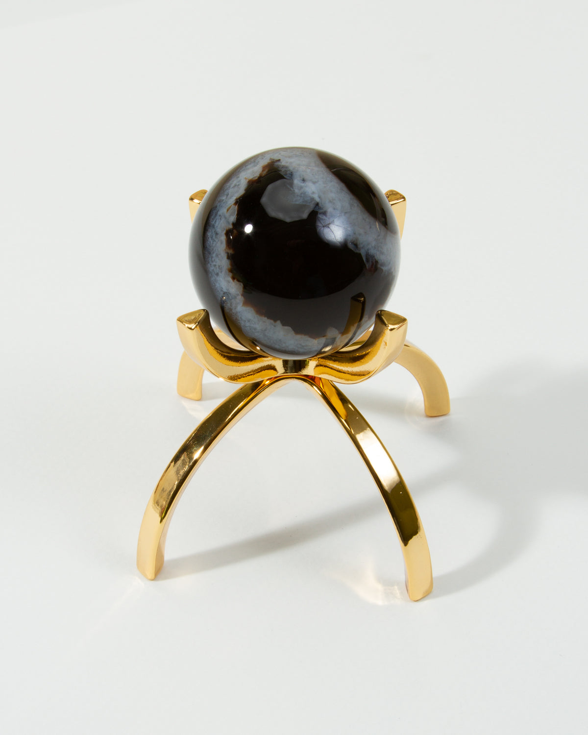 A sardonyx gemstone sphere on a gold-colored stand.
