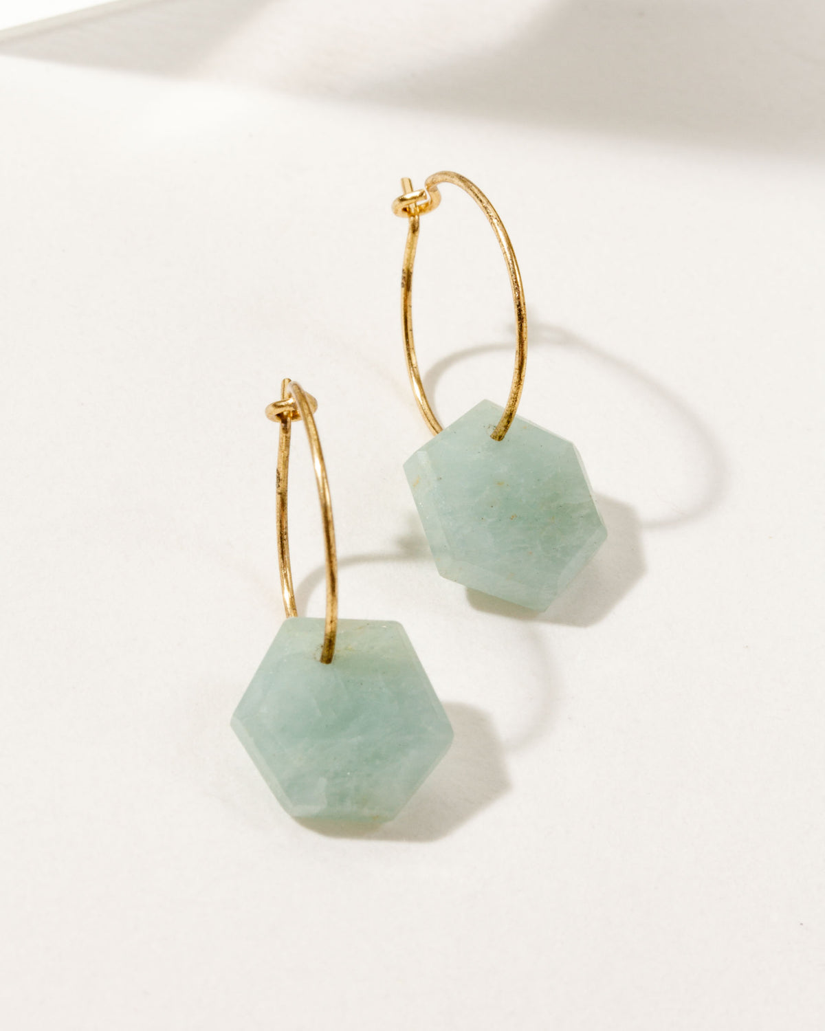 Blue-green aquamarine geometric shaped sterling silver hoop hearings on a white background.