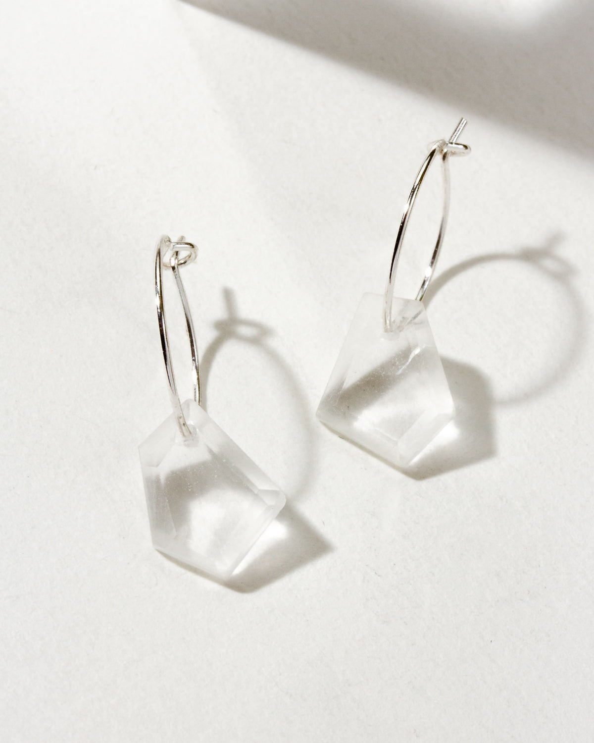 Clear quartz geometric shaped sterling silver hoop hearings on a white background.