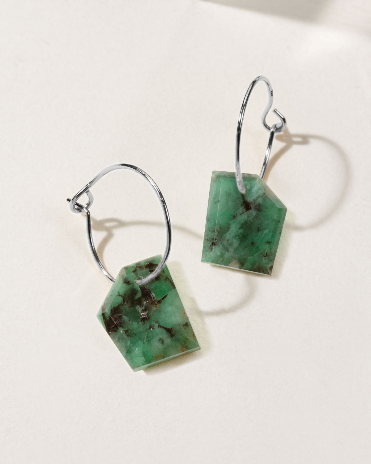 Green emerald geometric shaped sterling silver hoop hearings on a white background.