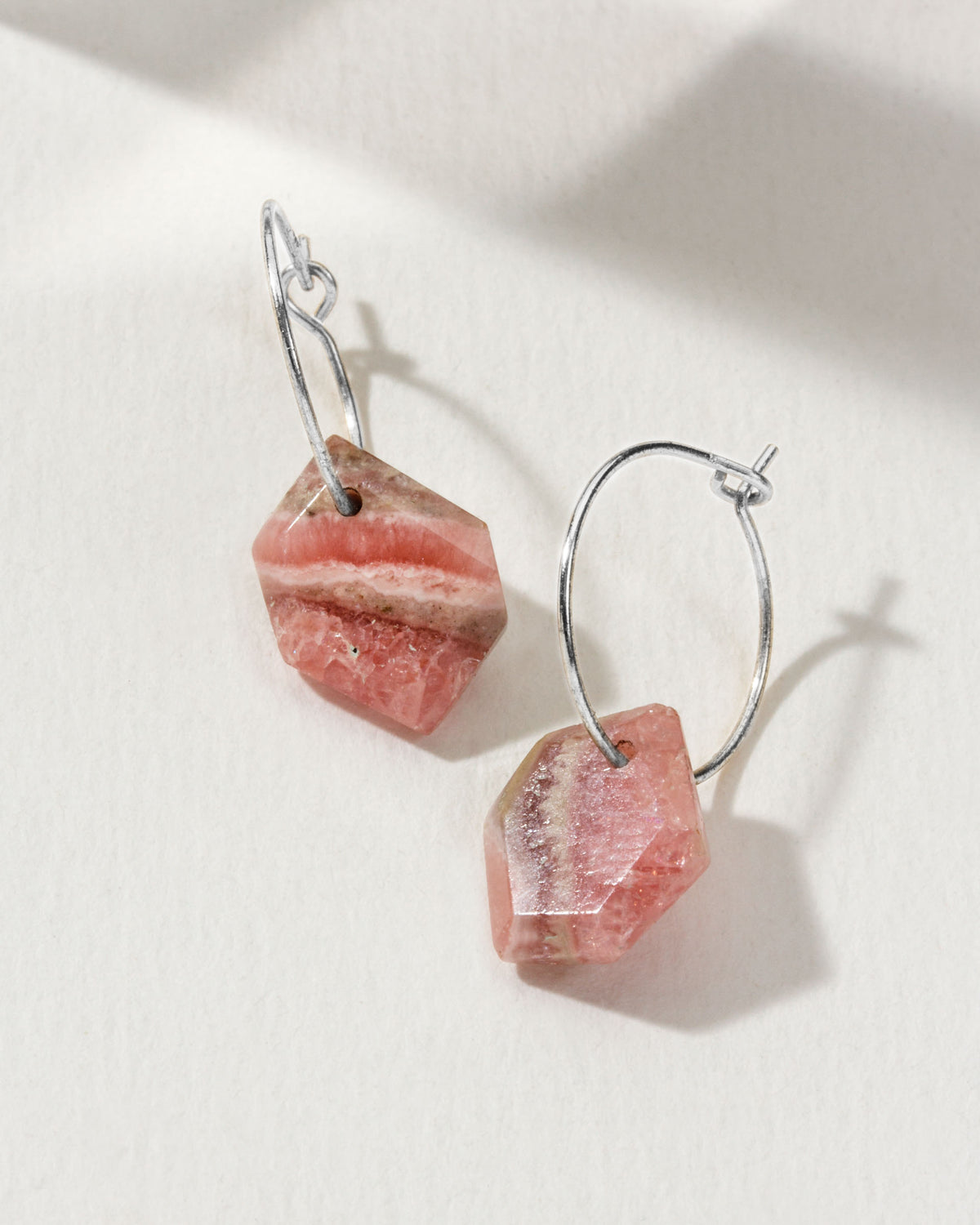 Pink Rhodochrosite geometric shaped sterling silver hoop hearings on a white background.