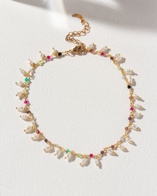 A gold metal anklet with multicolored multistone beads and pearls