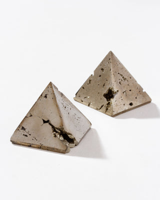 Two pyrite gold colored pyramid curios on a white background.