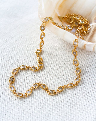 Gold bracelet with square cz gemstones on a textured white surface