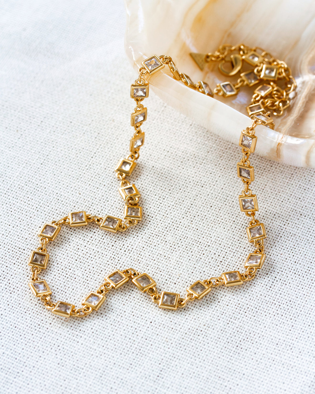 Gold bracelet with square cz gemstones on a textured white surface