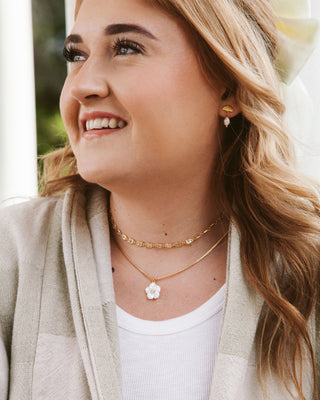 Woman wearing gold necklaces and earrings outdoors