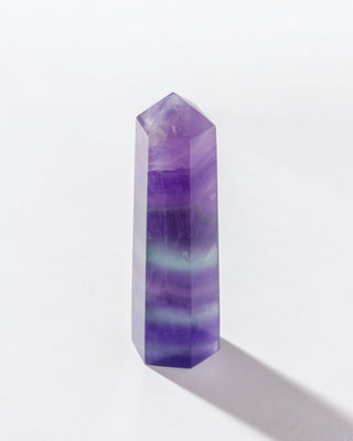 Flourite gemstone tower standing on a white background.