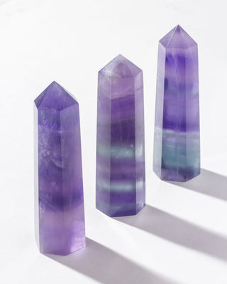 A hexagonal figure of genuine fluorite, with varying shades of violet, and white, displayed against a neutral background.