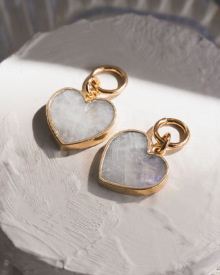 Pair of moonstone heart-shaped interchangeable earring charms attached to small gold-colored hoop earrings.