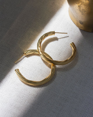Gold hoop earrings on a textured white surface