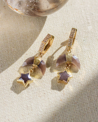 Coffee moonstone and cz moon, star, hoop earrings on a textured white surface.