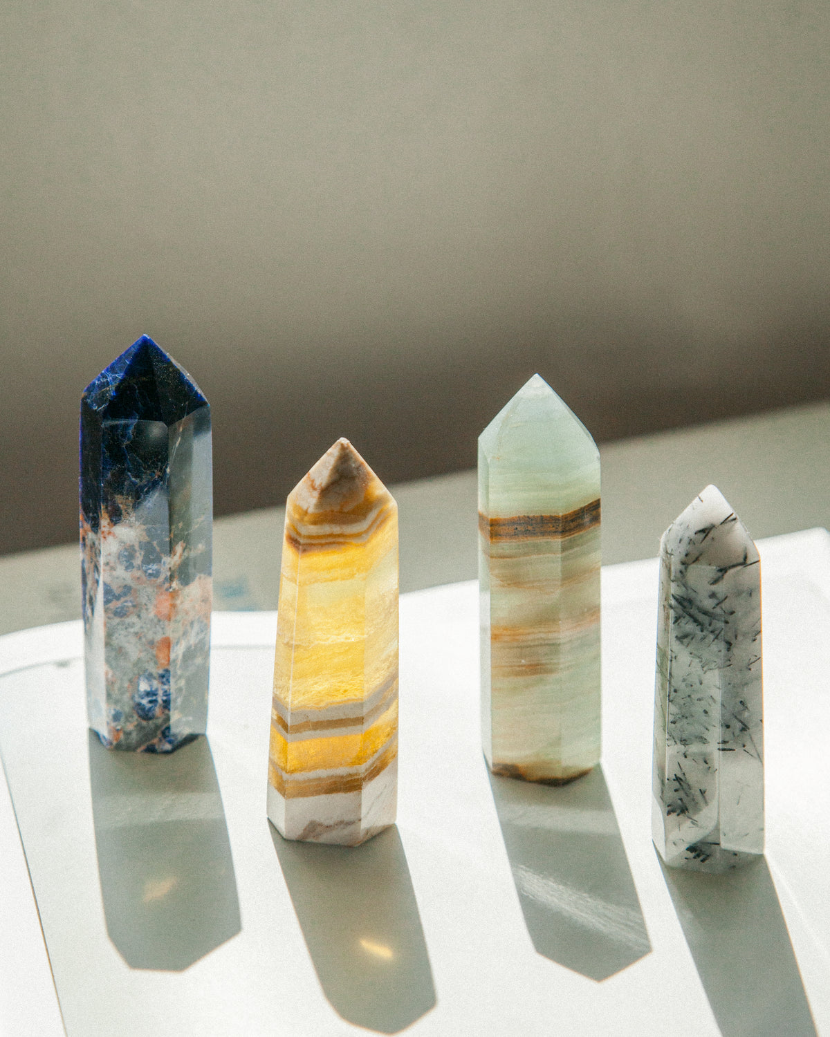 Four gemstone towers of varying colors: blue, yellow, green, and tourmalinated quartz.
