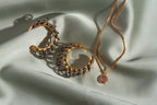 Two Golden Eclipse Vertebrae Post Hoop Earrings and a necklace with a pink gemstone