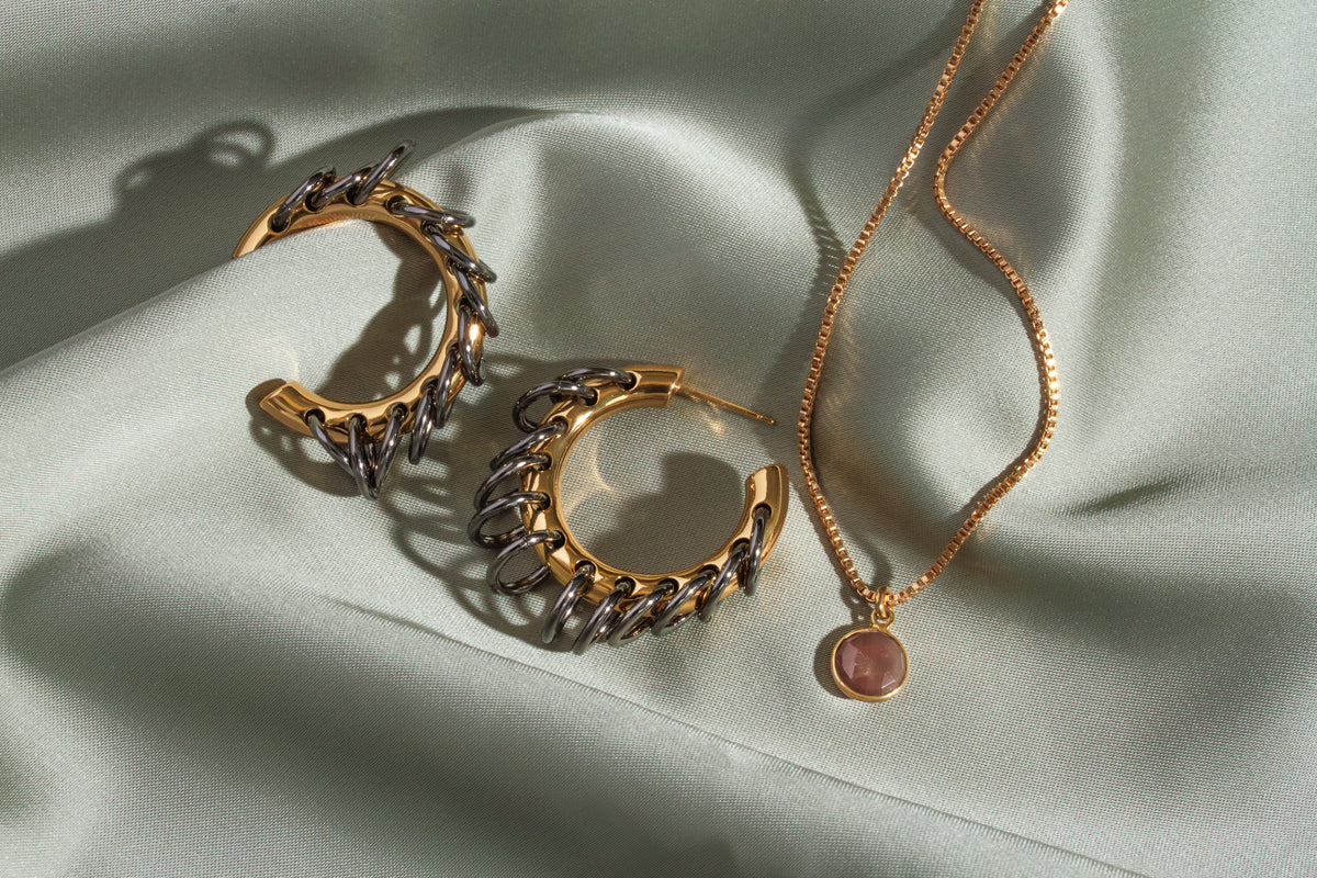 Two Golden Eclipse Vertebrae Post Hoop Earrings and a necklace with a pink gemstone