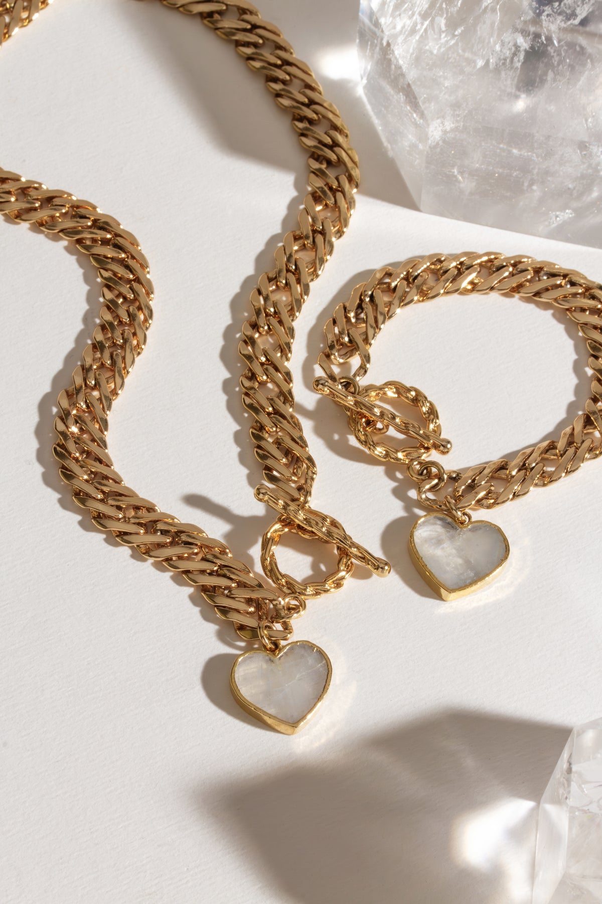 Gold chain necklace and bracelet with Mother of Pearl heart pendants and a toggle clasp.