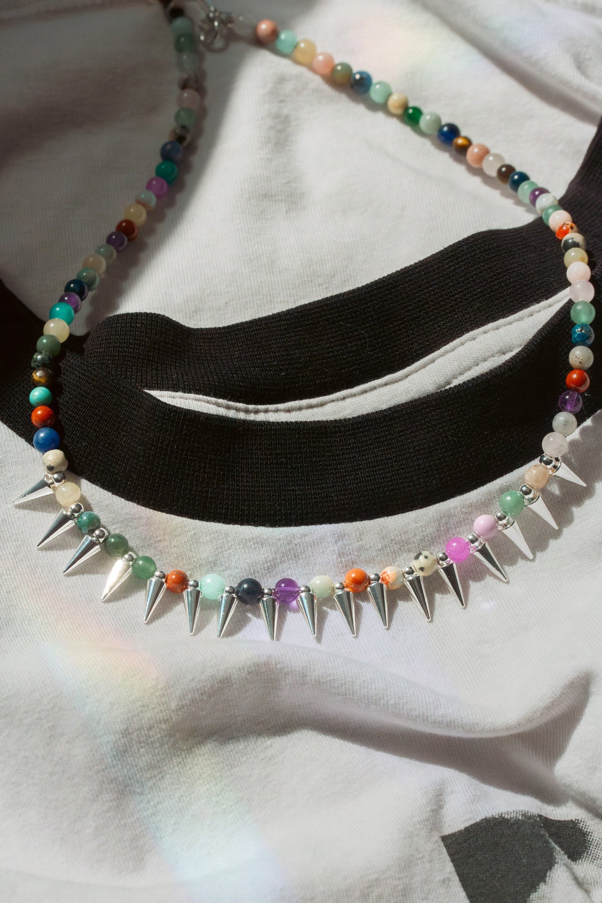 Necklace with colorful beads and silver spikes on a white and black ringer t-shirt
