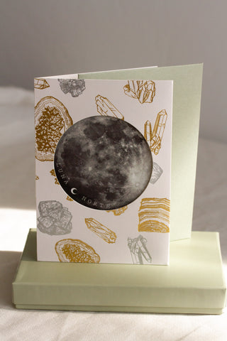 Gift card with crystal design with moon sticker placed on top of gift box and wrapping paper set