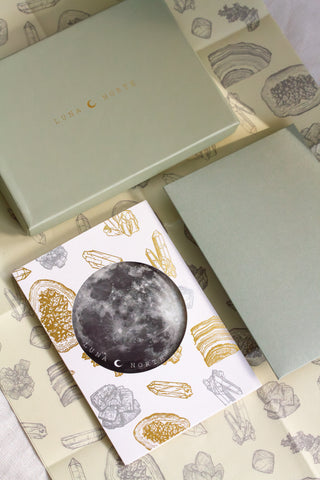 Gift card with crystal design with moon sticker placed on top of gift box and wrapping paper set