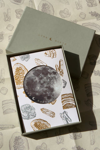 Gift card with crystal design with moon sticker placed on top of gift box and wrapping paper set