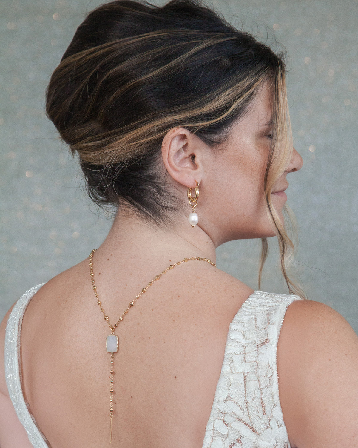 Woman wearing a delicate gold necklace with a gray background