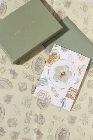 Greeting card with floral design on a matching box against a patterned background