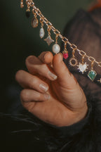 Woman holding a gold necklace with charms