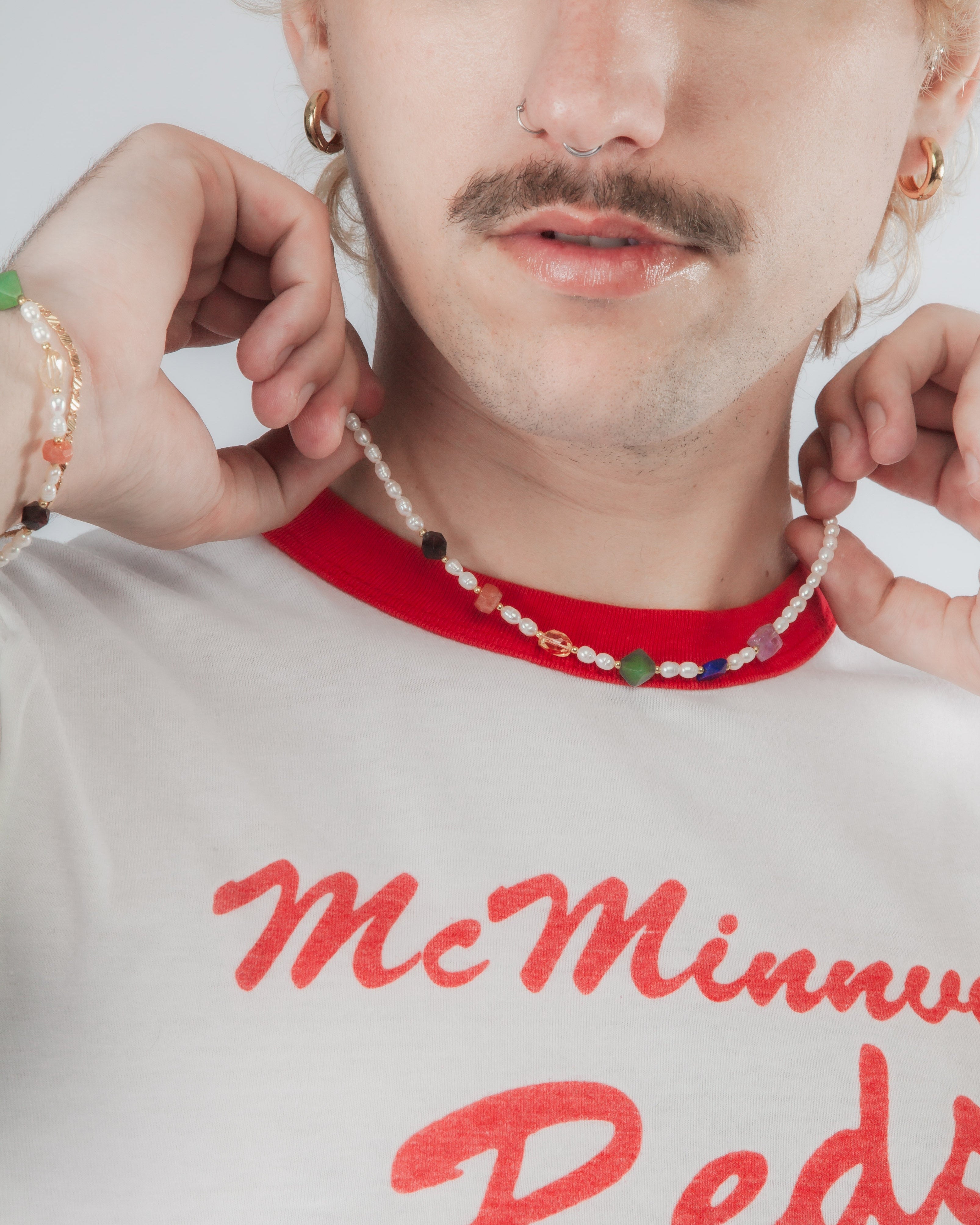 Person wearing a red and white ringer t-shirt and jewelry featuring freshwater pearl and genuine gemstones