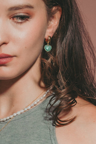 A model wearing amazonite heart wide huggie hoop earrings in gold.