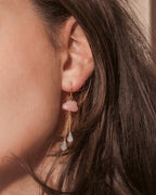Close-up of a woman's ear wearing pink cloud earrings with moonstone drops
