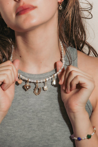 Model wearing pearl charm necklace with removable charms and pearl bracelet with genuine stones.