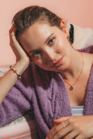 Model wearing round gemstone pendant and beaded pearl bracelet.