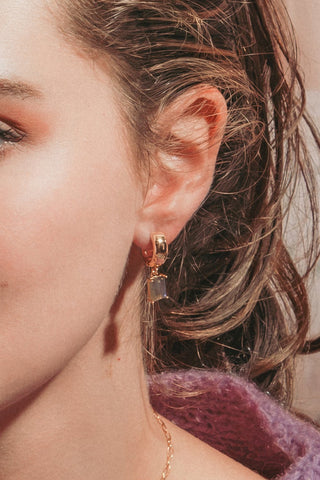 Model wearing gold and labradorite wide huggie hoop earring.