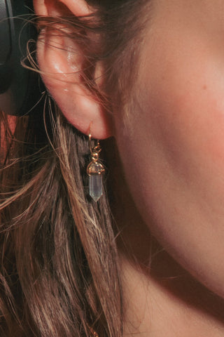 A close-up  shot of a woman wearing small crystal point dainty gold hoop.