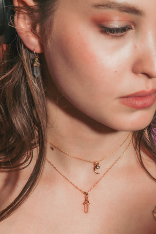 A close-up lifestyle shot of a woman wearing delicate gold chain necklaces with small charms.