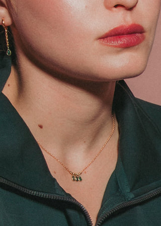 Model wear dainty emerald teardrop necklace and matching hoop earring.