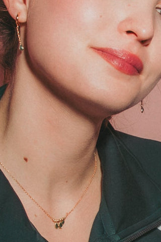 Model wearing dainty teardrop gemstone earring with matching necklace.