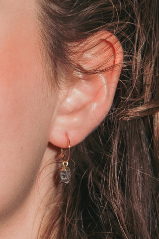 Closeup ear shot of dainty gold hoop with Herkimer gemstone.