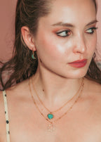 Woman in polka dot top, wears gold necklaces, one with amazonite pendant and another with CZ charm