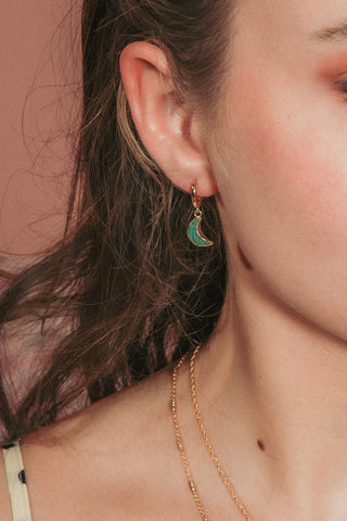 Model wearing green gemstone crescent moon huggie hoop earring.